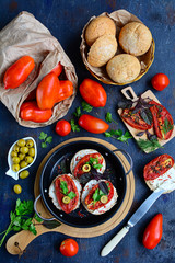 View of the table with sun-dried tomatoes, whole grain bread, herbs, olives. Italian sandwiches