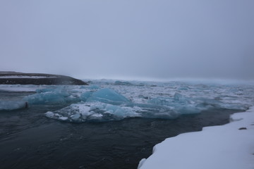 Fototapeta na wymiar アイスランドのヨークルスアゥルロゥン氷河湖で、氷河湖から氷が海に流れ出して ダイヤモンドビーチを形成しています。