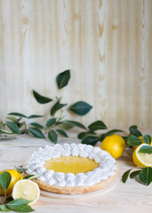 Fototapeta na wymiar Fresh homemade lemon pie with meringue on light wooden background, selective focus, vertical orientation