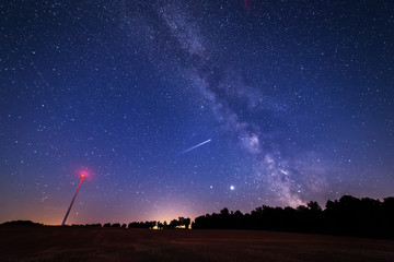 Milky Way Galaxy over a windmill field with falling star across.