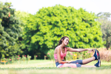 Portrait of fit and sporty young woman doing stretching outside in park
