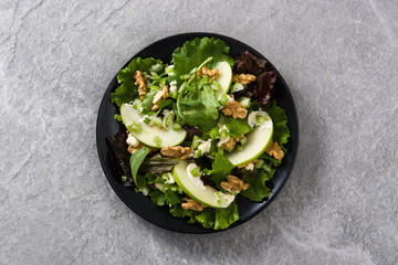 Fresh Waldorf salad with lettuce, green apples, walnuts and celery on gray stone. Top view
