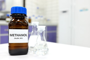 Selective focus of methanol brown amber glass bottle inside a laboratory. Blurred background with...