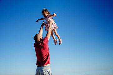 The father throws the baby up. Happy child plays with his father. Happy fatherhood. Father and daughter close-up.Happy father throws his little daughter up against the blue sky