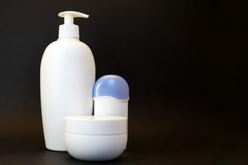 cosmetic white bottle with spray bottle, cream jar and deodorant on black background