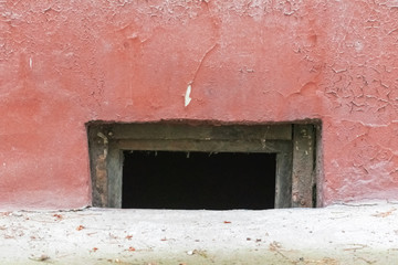 Basement window in an old red painted cracked wall