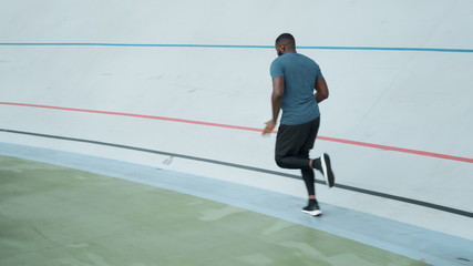 Fototapeta na wymiar Afro runner training on sports track. Sporty man running on athletics track