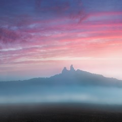 Ruins of old castle Trosky in Bohemian Paradise, Czech Republic. Ruins consist of two devasted towers on the woody hill. Morning landscape with misty atmosphere