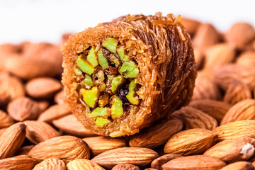 Turkish baklava with nuts in honey. Oriental sweets. A piece of baklava on a white background, lying on almonds.