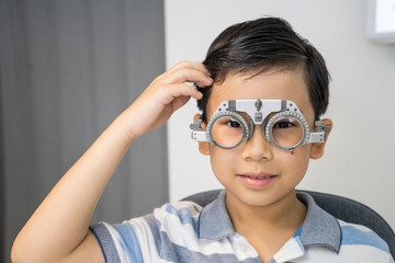 Boy put trial frame at clinic Medical Optician concept.