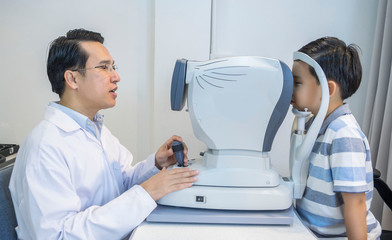 Obraz premium Eye doctor in medical concept. An eye doctor measured his eyesight for a boy with nearsightedness at an optician.