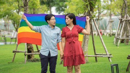 Happiness Lesbian couple was walking relax in the park with a LGBT rainbow flag. LGBT and bisexual concept
