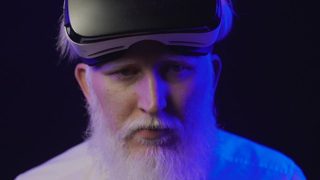Closeup view of old albino grandfather putting on a new vr set and smiling, isolated on a cool and unique background.