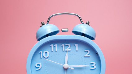 Alarm clock 12.15 o'clock isolated on pink background..