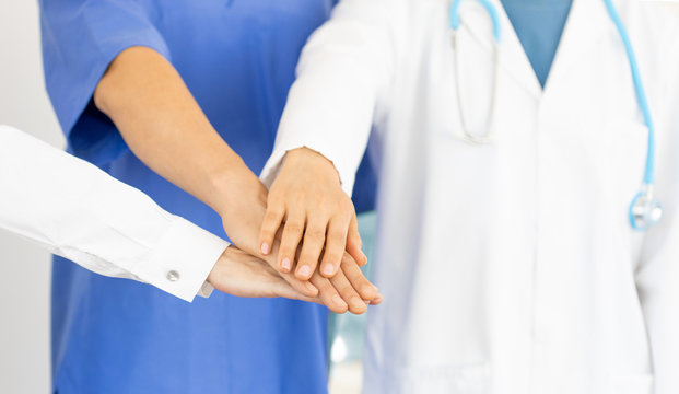 closeup of doctors joining their hands, concept of cooperation and teamworking in health care