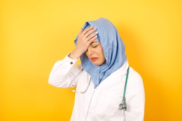 A very upset and lonely Young arab doctor woman wearing medical uniform standing over yellow...