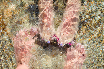 female feet with a pedicure in sea water