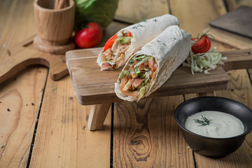 shawarma cutaway with vegetables and chicken on a wooden background