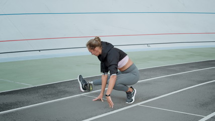 Disabled fit woman stretching legs on track. Lady preparing for workout outdoors