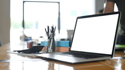 A computer laptop with a white blank screen is putting on a table in the living room.