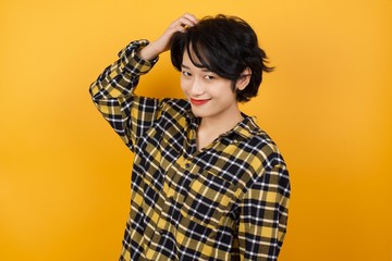 Young beautiful Asian woman wearing plaid shirt over yellow background being confused and wonders...