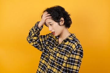 A very upset and lonely Young beautiful Asian woman wearing plaid shirt over yellow background crying, 