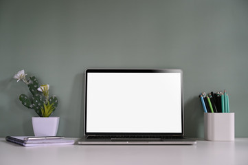 Workspace mockup laptop, pencil, notebook and cactus on desk with green background.