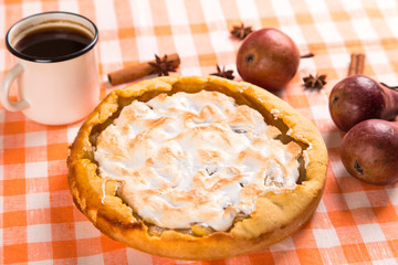 Pear pie with cream, homemade pastries on the table with a orange napkin, coffee and spices. Copy space.