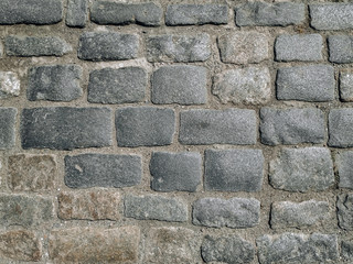 Vintage texture of dark gray granite paving stones, top view. Background from natural block stone.