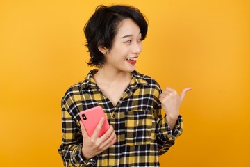 Portrait of Arab businesswoman wearing red shirt using and texting with smartphone over isolated background pointing and showing with thumb up to the side with happy face smiling