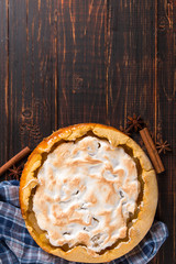 Pear pie with cream, homemade pastries on the wooden table, with spices. Copy space.