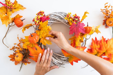 Florist at work: woman makes an autumn wreath at the door from yellow leaves, decorative pumpkins and berries. Top View