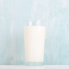Milk in a glass glass on the table on a blue background. Copy space.
