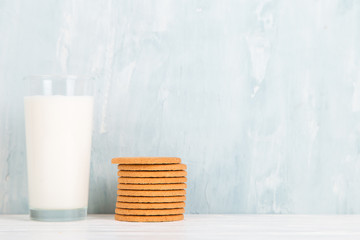 A glass of milk and cookies on the table, on a blue background, minimalism. Copy space.
