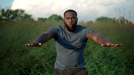 Athletic man doing squats in park. Athlete breathing deeply during workout