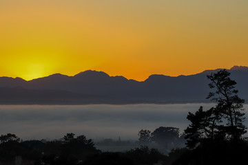 Sunrise in Cape Town from the Durbanville area showing mountain range and fog bank