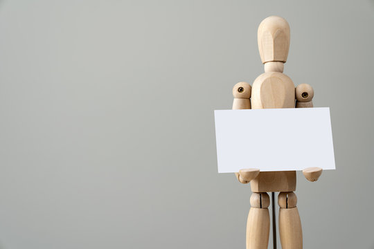 Wooden figure mannequin holding blank name card in hand