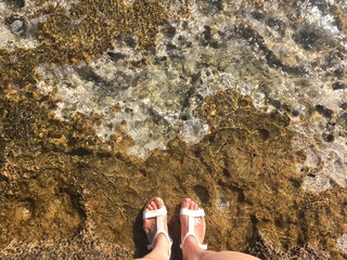 Sea coast. Sea waves envelop women's legs with sea foam. Wallpaper, backdrop and postcard.