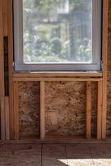interior view of a window and framed wall showing studs and sheathing under construction