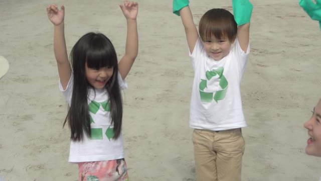 Happy asian family team volunteer keeping garbage and plastic bottle while cleaning on beach for reduce pollution and toxic and recycle to environment for protect and help social in summer together.