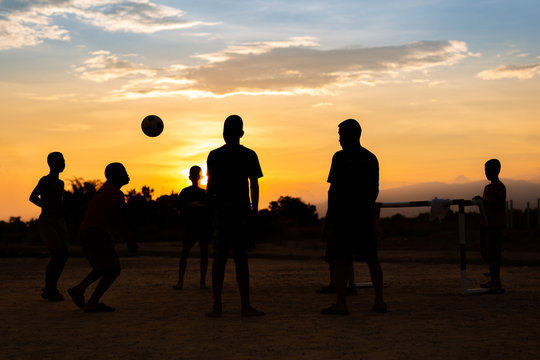 Silhouette action sport of a group of kids playing soccer football for exercise under the sunset.
