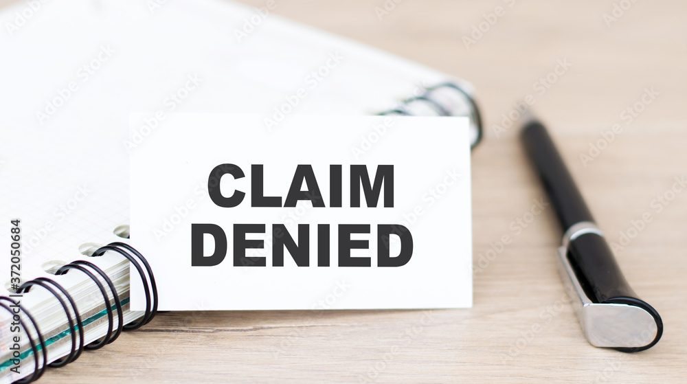Poster a card with text claim denied on the table near the notebook
