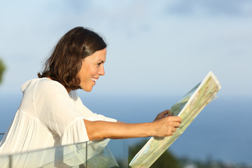 Adult woman searching location in a map from a balcony