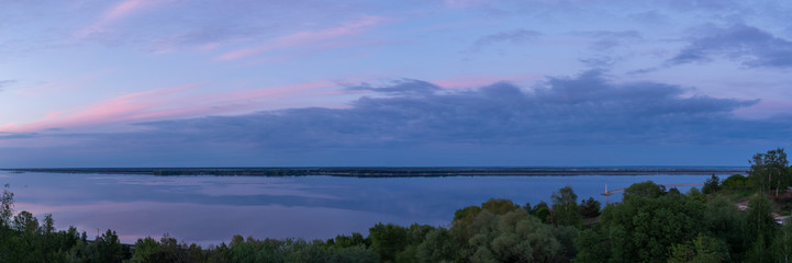 Panoramic photo of nature by the water. Panorama at sunset. Overcast sky.