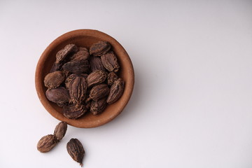 Black cardamom whole seeds in a bowl on white background indian spice with copyspace top view