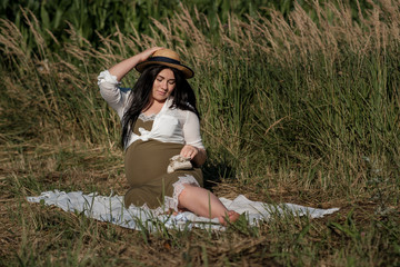 Naklejka na ściany i meble Pregnant girl in a hat on the nature. Enjoy pregnancy. Lonely young mother. An authentic homeland.