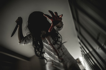 Woman in ghost or zombie on halloween festival at dark place, holding knife and wants to stab you....