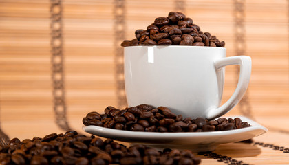 white cup with white saucer filled with coffee beans