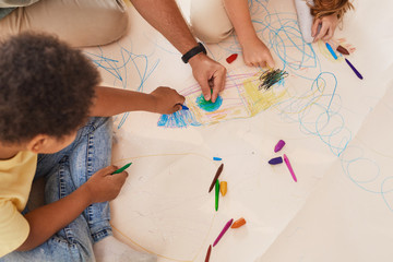 High angle closeup of unrecognizable male teacher working with kids drawing pictures while having...