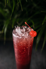 Cocktail drink on a old stone board. Alcoholic beverage with tropical fruits red pepper herb and ice. cocktail in glass on black background. Copyspace. Close up of glass of cocktail 